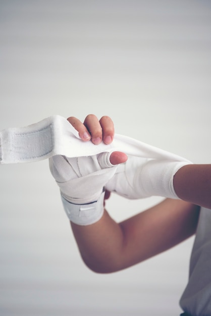 Jovem boxeador envolvendo mãos com envoltórios de boxe