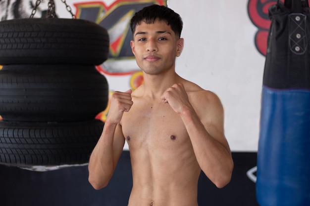 Jovem boxeador latino com punhos levantados sorrindo posando para a câmera