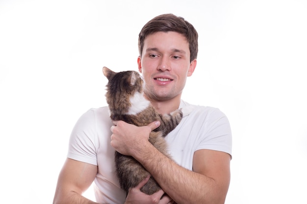 Jovem branco bonito segura ternamente um gato em suas mãos em um fundo branco