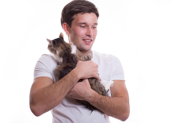 Jovem branco bonito segura ternamente um gato em suas mãos em um fundo branco