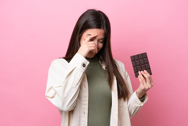 Jovem brasileira com chocolate isolado no fundo rosa rindo