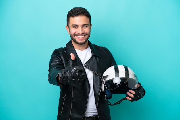 Jovem brasileira com um capacete de moto isolado em fundo azul com polegares para cima porque algo bom aconteceu