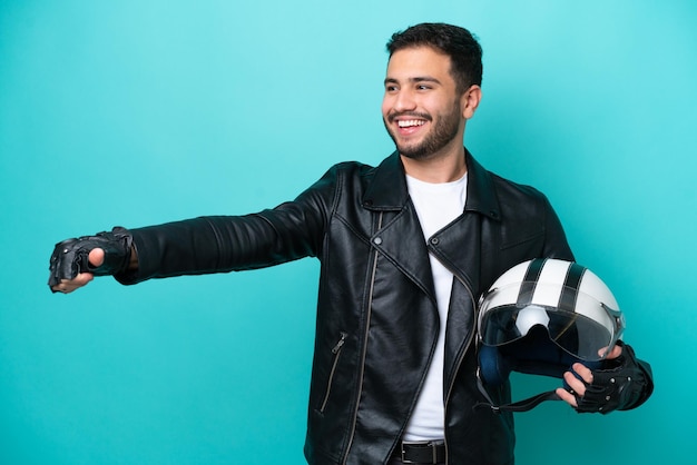 Jovem brasileira com um capacete de moto isolado em fundo azul dando um polegar para cima gesto