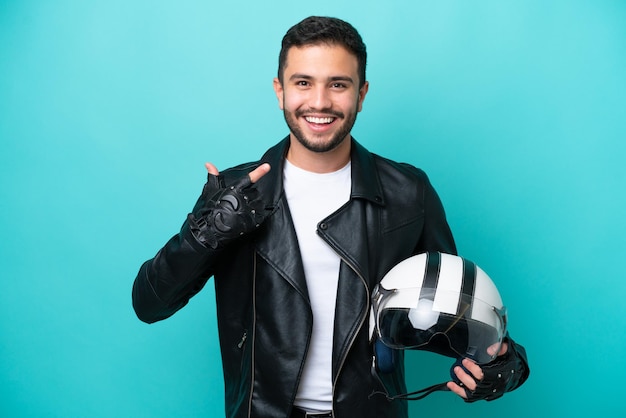 Jovem brasileira com um capacete de moto isolado em fundo azul dando um polegar para cima gesto