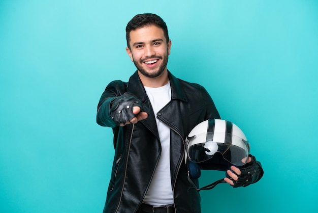 Jovem brasileira com um capacete de motocicleta isolado em fundo azul surpreso e apontando para frente