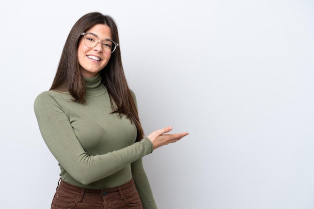 Jovem brasileira isolada em fundo branco apresentando uma ideia enquanto olhava sorrindo para