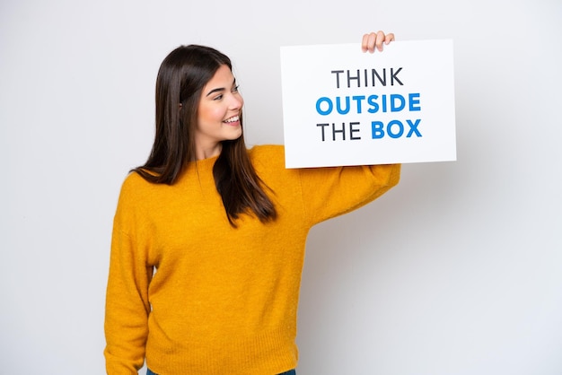 Jovem brasileira isolada em fundo branco segurando um cartaz com texto Think Outside The Box