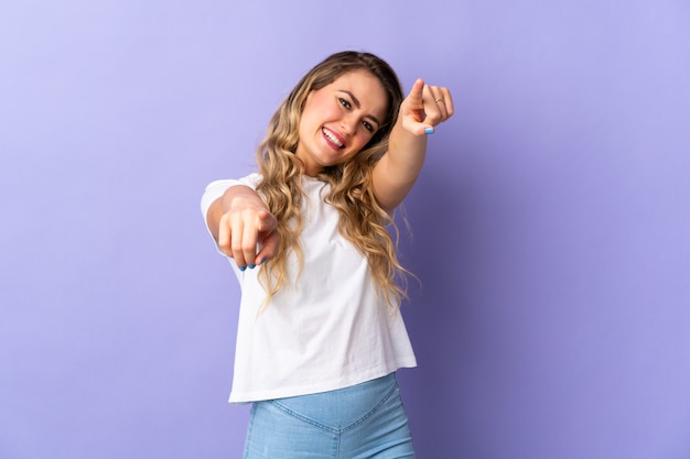 Jovem brasileira isolada na frente apontando roxo com expressão feliz