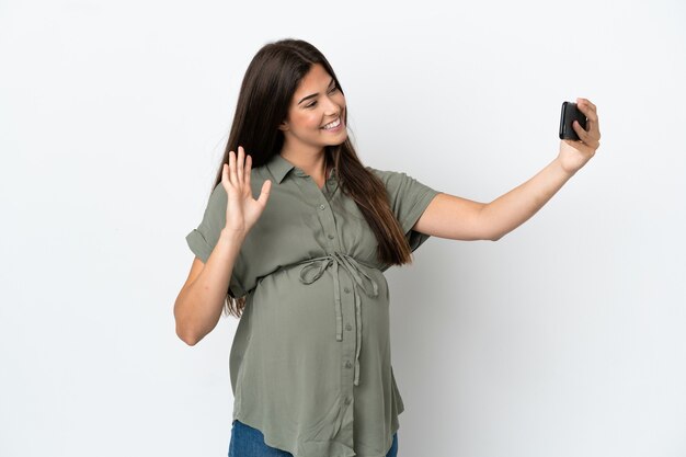 Jovem brasileira isolada no fundo branco grávida e fazendo selfie