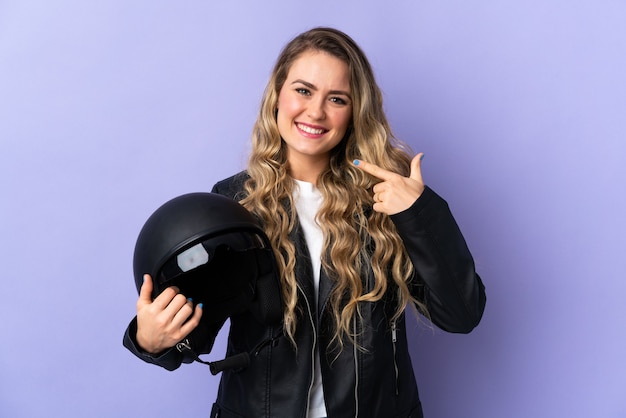 Jovem brasileira segurando um capacete de motociclista isolado em roxo e fazendo um gesto de polegar para cima