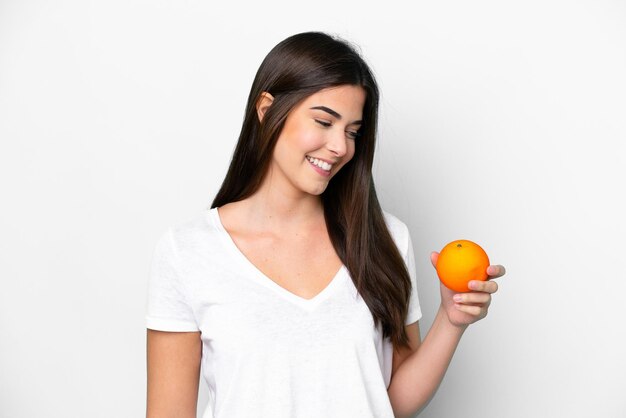 Jovem brasileira segurando uma laranja isolada no fundo branco com expressão feliz