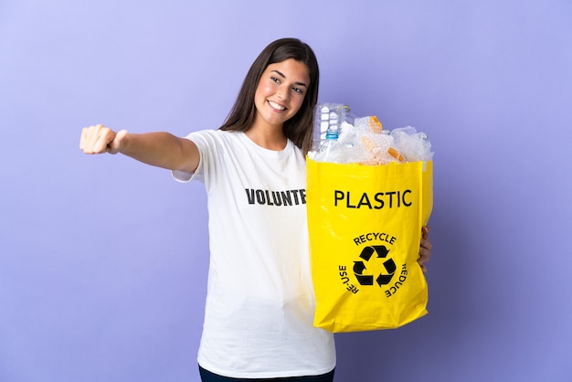 Jovem brasileira segurando uma sacola cheia de garrafas plásticas para reciclar isolada