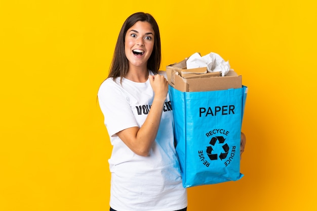 Jovem brasileira segurando uma sacola de reciclagem cheia de papel para reciclar isolada