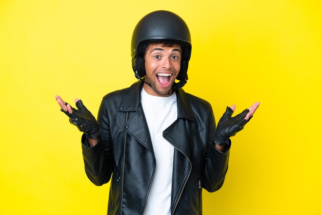 Jovem brasileiro com capacete de motociclista isolado em fundo amarelo com expressão facial de choque