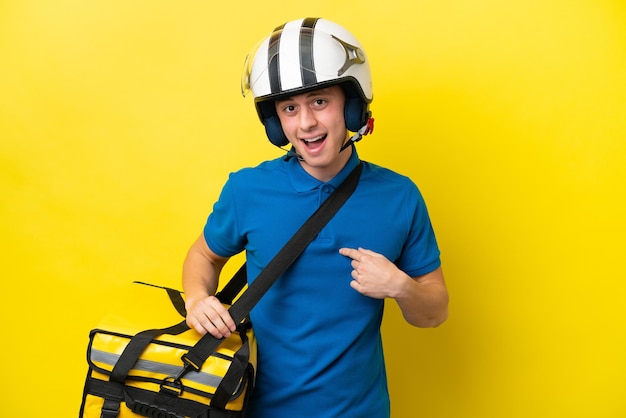 Jovem brasileiro com mochila térmica isolada em fundo amarelo com expressão facial de surpresa