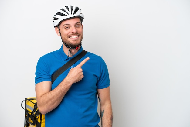 Jovem brasileiro com mochila térmica isolada em fundo branco apontando para o lado para apresentar um produto