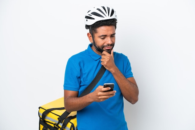 Jovem brasileiro com mochila térmica isolada em fundo branco pensando e enviando uma mensagem