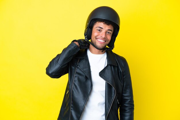 Jovem brasileiro com um capacete de motociclista isolado em um fundo amarelo rindo