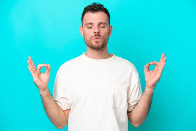 Jovem brasileiro isolado em fundo azul em pose zen