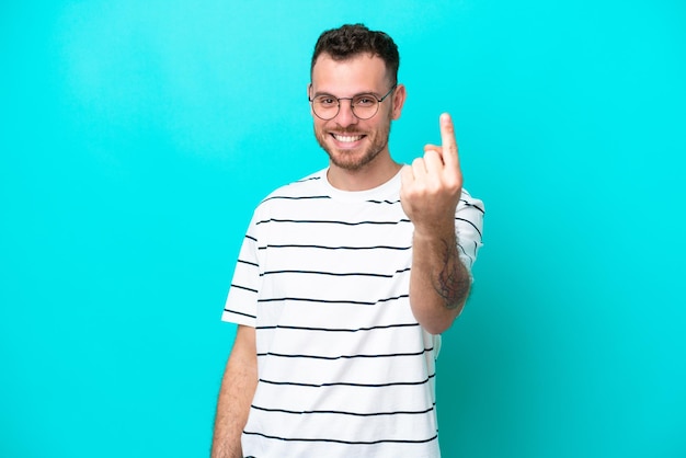 Jovem brasileiro isolado em fundo azul fazendo gesto de vinda