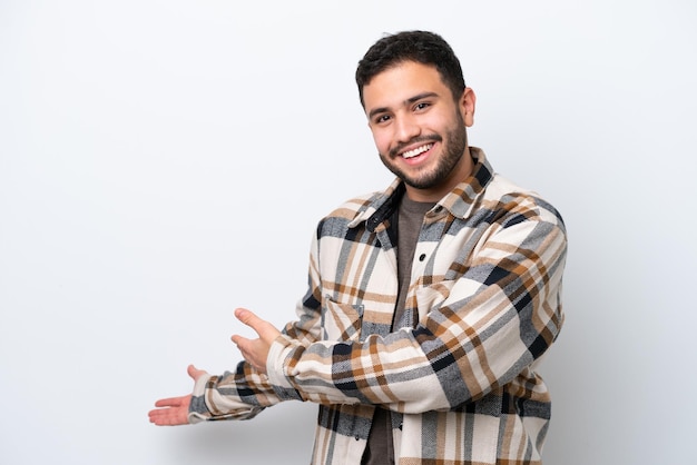 Jovem brasileiro isolado em fundo branco, estendendo as mãos para o lado por convidar para vir