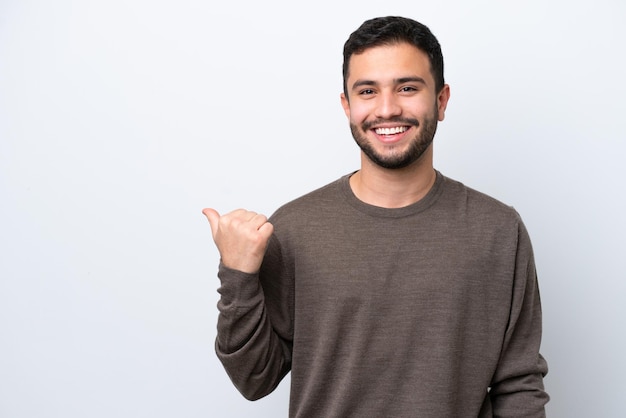 Jovem brasileiro isolado no fundo branco apontando para o lado para apresentar um produto