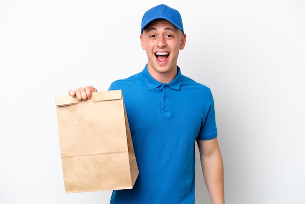 Jovem brasileiro levando um saco de comida para viagem isolado no fundo branco com expressão facial de surpresa