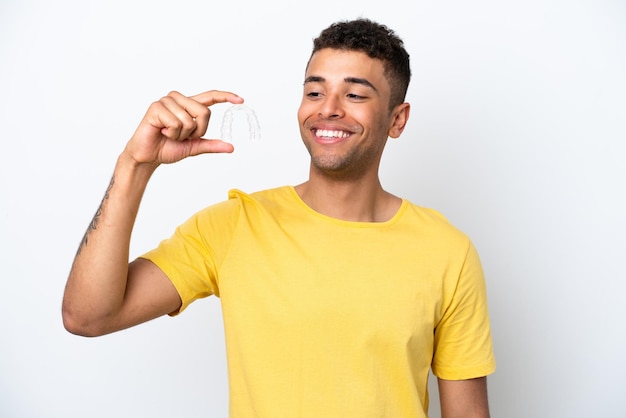 Jovem brasileiro segurando aparelho invisível isolado no fundo branco com expressão feliz