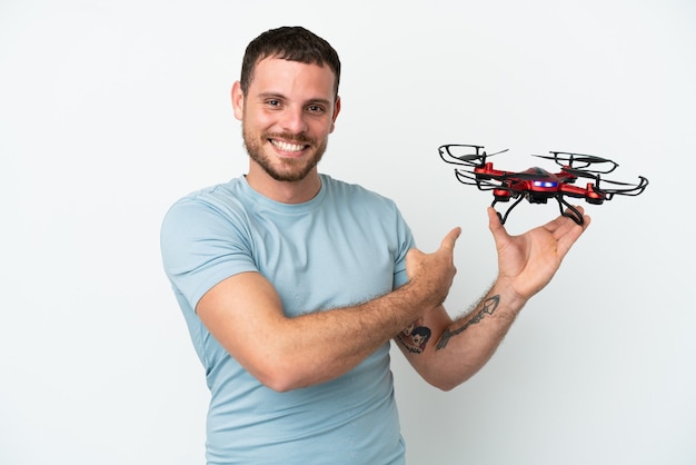 Jovem brasileiro segurando um drone isolado no fundo branco apontando para trás