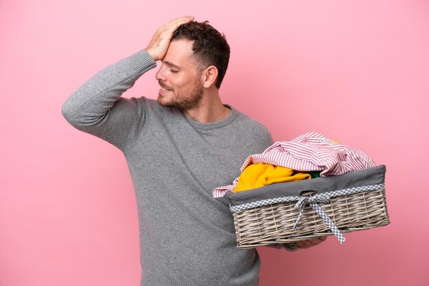 Jovem brasileiro segurando uma cesta de roupas isolada em fundo rosa percebeu algo e pretende a solução