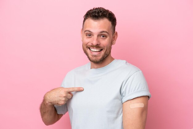 Jovem brasileiro vestindo um curativo isolado no fundo rosa com expressão facial de surpresa