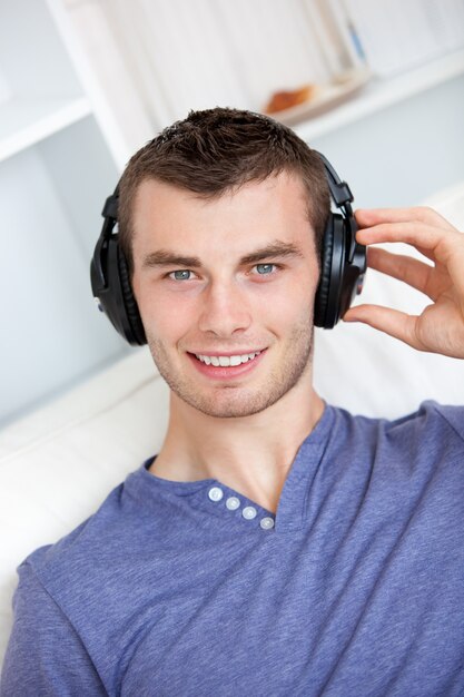 Jovem brilhante ouvindo música sentada no sofá na sala de estar