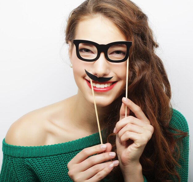 Jovem brincalhona segurando óculos de festa e bigode falso