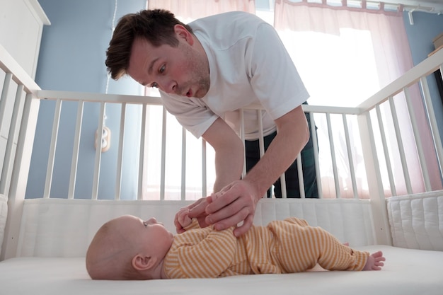 Jovem brincando com seu bebê na cama