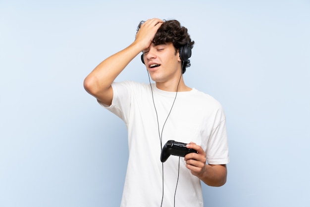 Jovem brincando com um controlador de videogame sobre parede azul isolada percebeu algo e pretendia a solução