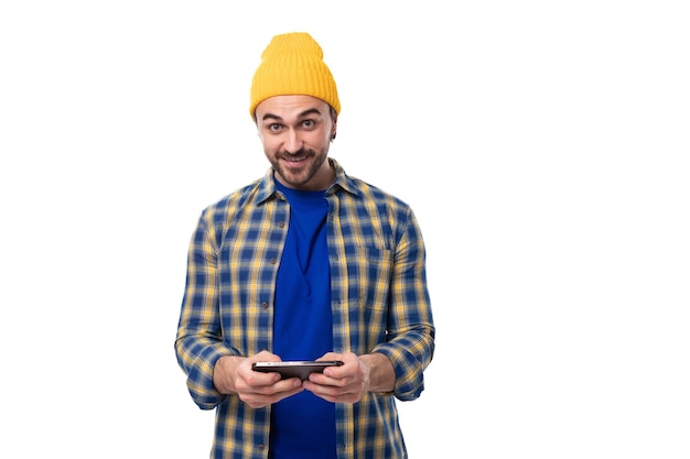 Foto jovem brunete europeu bem cuidadoso com barba e bigode vestido com um chapéu amarelo e azul