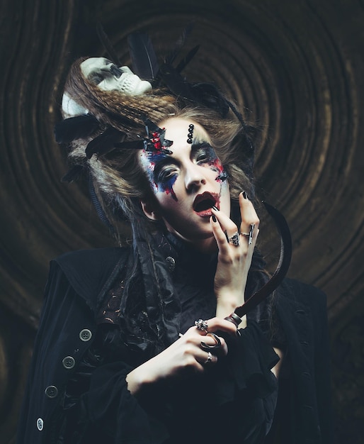 Jovem bruxa segurando foice Brilhante maquiagem crânio fumaça tema de halloween