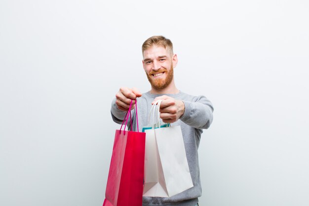 Jovem cabeça vermelha com sacos de compras contra branco