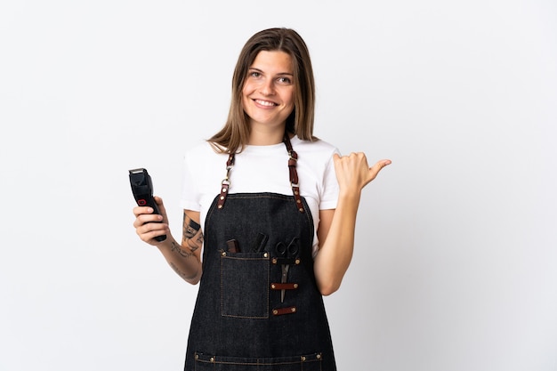 Jovem cabeleireira eslovaca isolada num fundo branco apontando para o lado para apresentar um produto