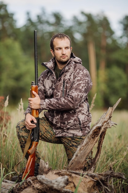 Jovem caçador masculino em roupas de camuflagem pronto para caçar com rifle de caça