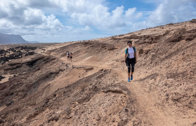 Jovem caminhando ao longo das falésias e praias intocadas na ilha de La Graciosa Ilhas Canárias