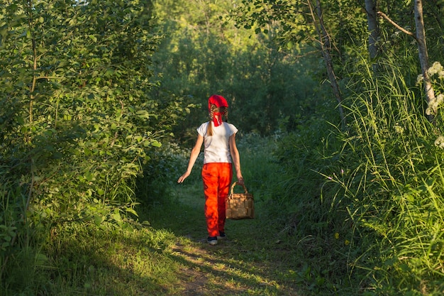 Jovem caminhando em um caminho pela floresta verde carregando uma cesta de casca de árvore