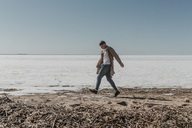 Jovem caminhando na praia de inverno.