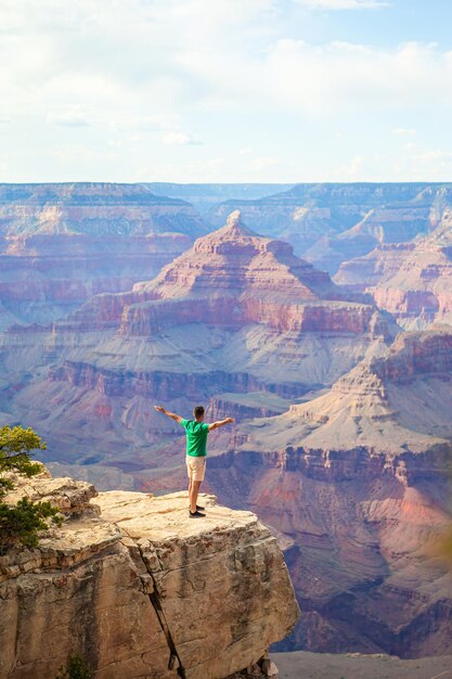 Jovem caminhante está de pé em um penhasco íngreme admirando a vista incrível sobre o famoso Grand Canyon Arizona EUA