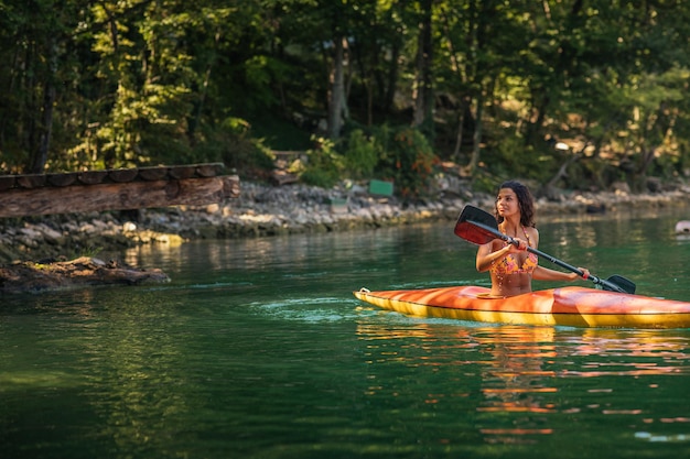 Jovem canoagem em um lago em um dia de verão