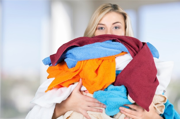 Foto jovem cansada carregando uma pilha de roupas diferentes