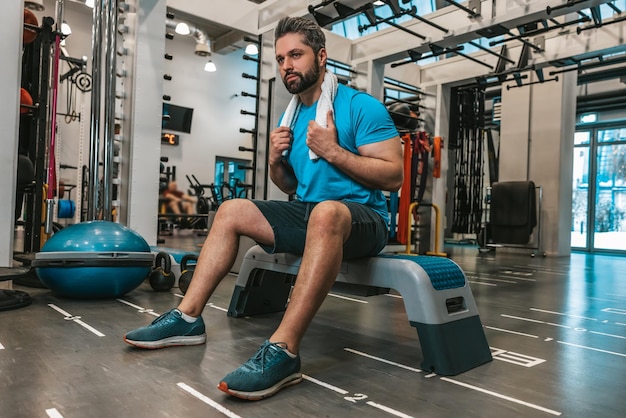 Jovem cansado sentado e descansando após o treino