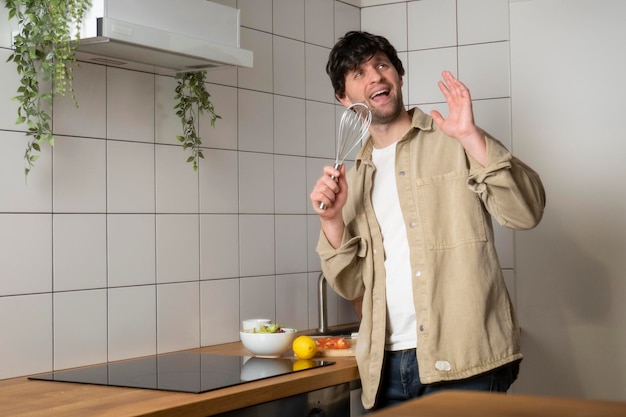 Jovem canta em um batedor enquanto prepara o café da manhã em um interior de cozinha moderno