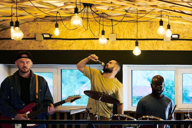 Foto jovem cantor masculino tocando música enquanto segura o microfone pela boca