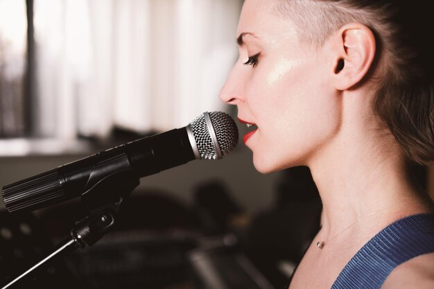 Foto jovem cantora de rock com microfone cantando mulher com cabelo curto apresentação de música ao vivo